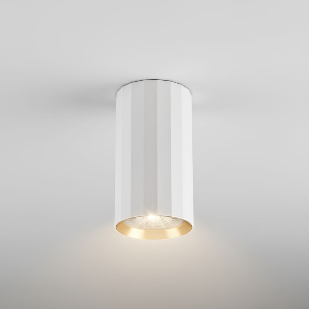 Biała lampa sufitowa w formie tuby z metalicznym złotym wnętrzem, montowana na suficie. Widoczny detal źródła światła GU10 oraz teksturowana powierzchnia. Ujęcie frontalne, na jednolitym tle.