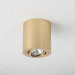 Złota lampa sufitowa Tulon LP-5441/1SM GD w kształcie cylindrycznym, z widocznym źródłem światła w środku. Ujęcie z dołu, pokazujące kierunkowe oświetlenie. Prosta, matowa powierzchnia, zamontowana na białym suficie.