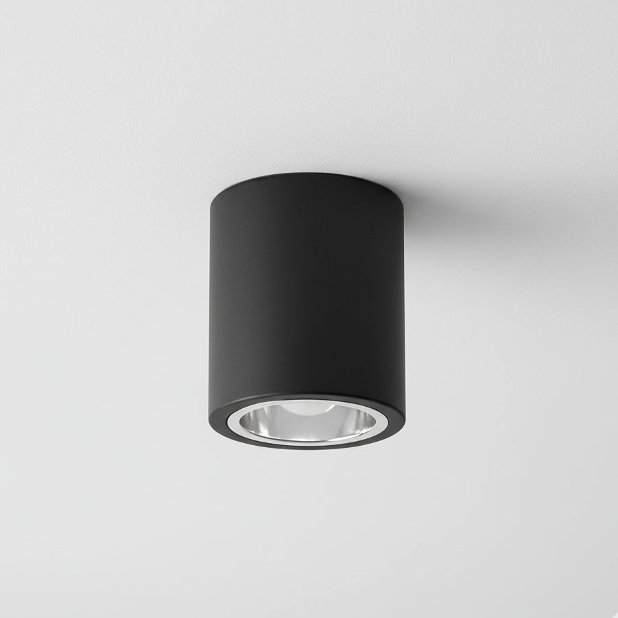 Czarna lampa sufitowa natynkowa Jupiter 10 w formie tuby, z oprawką na żarówkę E27. Produkt zamontowany na białym suficie, o cylindrycznym kształcie z widoczną metalową osłoną.