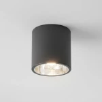 Lampa sufitowa natynkowa Jupiter 17 w kształcie czarnej tuby, z pojedynczym gniazdem E27. Umieszczona na białym suficie, emitująca ciepłe światło przez przezroczystą szybkę. Prosta, cylindryczna forma, idealna do nowoczesnych wnętrz.