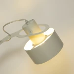 Lampa stołowa Rif 1xE27 w odcieniu szaro-beżowym, z okrągłym kloszem i metalową konstrukcją. Ujęcie z góry, pokazujące źródło światła oraz charakterystyczny kształt. Jasne światło wydobywające się z klosza.