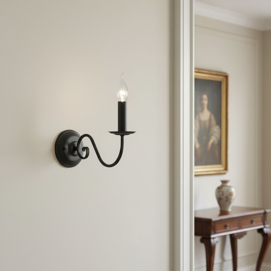 Czarny kinkiet Asti 1-punktowy z metalowym ramieniem w kształcie spirali, z płomieniem w formie szklanej świecy. Montowany na jasnej ścianie, obok obrazu i mebla, tworzy elegancką aranżację oświetleniową.