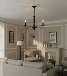 Czarny żyrandol Asti 3-punktowy O2893 W3 CZA z trzema ramionami, zawieszony na delikatnym łańcuchu. W tle elegancki salon z jasnymi ścianami, sofą i lampą stojącą. Oświetlenie podkreśla detale wnętrza.