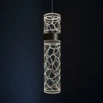 Lagos lampa wisząca LED 8W 4000K w złotym kolorze, o cylindrycznym kształcie z geometrycznym wzorem. Zawieszona na cienkim kablu, emituje ciepłe światło, idealna do nowoczesnych wnętrz. Tło ciemne, co podkreśla jej design.