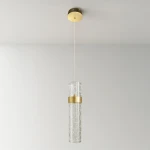 Lagos lampa wisząca LED 8W 4000K w złotym kolorze. Szklany klosz z dekoracyjnym wzorem, zawieszony na cienkim przewodzie. Ujęcie frontalne, lampa w pozycji wiszącej, na jasnym tle.
