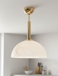 Lampa wisząca Klara z metalowym, złotym wykończeniem. Klosz w kształcie półkuli w delikatnym, mlecznym odcieniu. Montowana pod sufitem, z długim metalowym ramieniem. Idealna do nowoczesnych wnętrz.