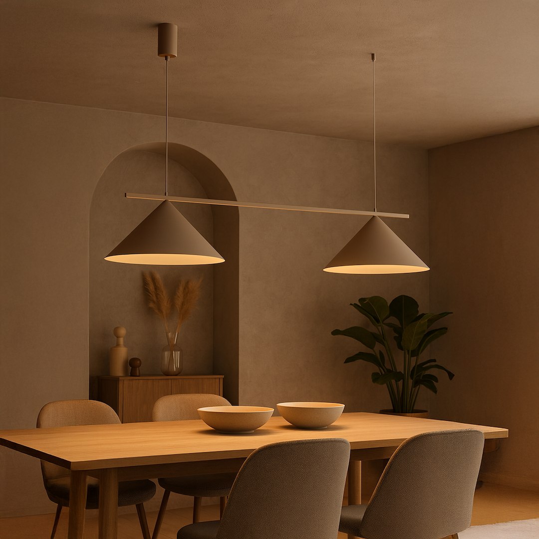 Lampa wisząca Capital w kolorze taupe, z dwoma kloszami w kształcie stożka, zawieszona na cienkiej rurce, oświetlająca stół w nowoczesnej aranżacji wnętrza. Tło w odcieniach beżu, z rośliną i drewnianymi meblami.
