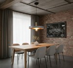 Lampa wisząca Dario z oprawą w kolorze szaro-złotym, zawieszona nad drewnianym stołem w jadalni. Surowe tło z cegły i zasłony w jasnym kolorze. Widoczne siedzenia w szarości i dekoracyjny wazon na stole.