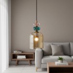 Lampa wisząca Busco z kloszem w kształcie dzwonu, wykonana z bursztynowego szkła, z kolorowymi akcentami w odcieniach różu i zieleni. Zawieszona na czarnym kablu, umieszczona w nowoczesnym wnętrzu z szaro-beżową sofą i drewnianym stolikiem.