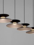 Guanay lampa wisząca z pięcioma kloszami LED, czarna z złotymi detalami. Klosze mają kształt talerzy, zawieszone na cienkich linkach, emitują ciepłe światło. Tło w odcieniu szarości podkreśla elegancki design lampy.