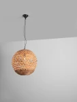 Lampa wisząca Guardia z materiału przypominającego hiacynt wodny, w kształcie dużej kuli. Ma czarny stelaż i jest zawieszona na cienkim łańcuchu. Widoczna żarówka E27 wewnątrz, otoczona plecionką w odcieniach brązu. Tło szare, minimalistyczne.
