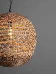 Lampa wisząca Guardia z czarnym przewodem, wykonana z hiacyntu wodnego, o okrągłym kształcie z plecionki, z widoczną żarówką E27. Zawieszona w lekkim kącie, na jednolitym szarym tle, podkreślająca naturalny materiał i fakturę.