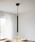 Lampa wisząca Piero w kolorze czarnym, o smukłej, cylindrycznej formie, zawieszona na czarnym kablu. Oświetlenie skierowane w dół, umieszczona nad stołem, w jasnym wnętrzu z białymi zasłonami. Szklane naczynie z kwiatami na stole oraz nakrycia.