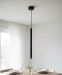 Czarna lampa wisząca Piero z jedną oprawą G9, o smukłej cylindrycznej formie, zawieszona na cienkim przewodzie. W tle stół nakryty talerzami i kieliszkami, z delikatnymi kwiatami w wazonie, w jasnym wnętrzu z białymi zasłonami.