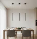 Czarna lampa wisząca Piero z jednym gniazdem G9, zawieszona na cienkim kablu, w minimalistycznym stylu. Zestaw trzech lamp w nowoczesnej aranżacji jadalni, nad drewnianym stołem z szarymi krzesłami. Jasne tło z dużymi oknami.