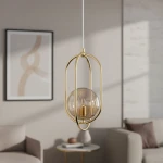 Lampa wisząca Binar 1-punktowa w kolorze złotym, z transparentnym kloszem w kształcie kuli, zawieszona na białym przewodzie. Widoczny elegancki metalowy stelaż oraz podstawa lampy. Tło w stonowanych kolorach, z elementami aranżacji wnętrza.