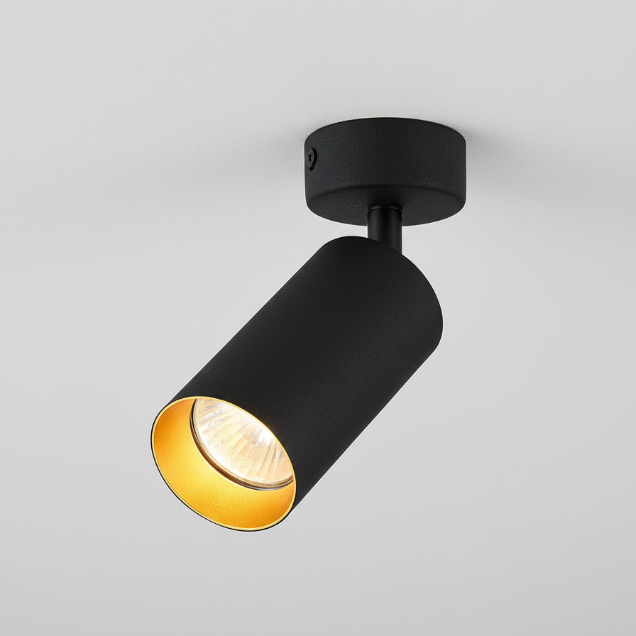 Czarna lampa sufitowa Eris w formie 1-punktowego spotu z cylindrycznym kloszem. Wnętrze klosza w kolorze złotym, zamontowana na czarnym stelażu. Ujęcie z góry, pokazujące kąt nachylenia klosza. Prosta, nowoczesna forma, idealna do oświetlenia wnętrz.