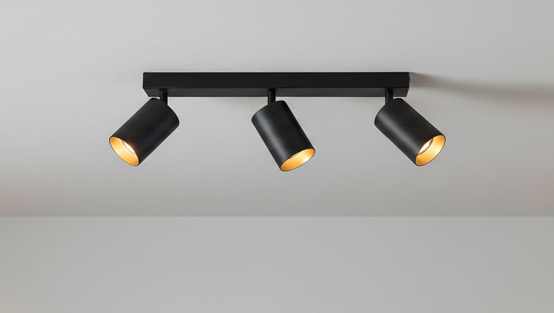 Czarna lampa sufitowa Eris z trzema punktami świetlnymi, w której wnętrzu znajduje się złoty element. Ujęcie z góry, ukazujące zamontowane reflektory o cylindrycznym kształcie, skierowane w różne strony.