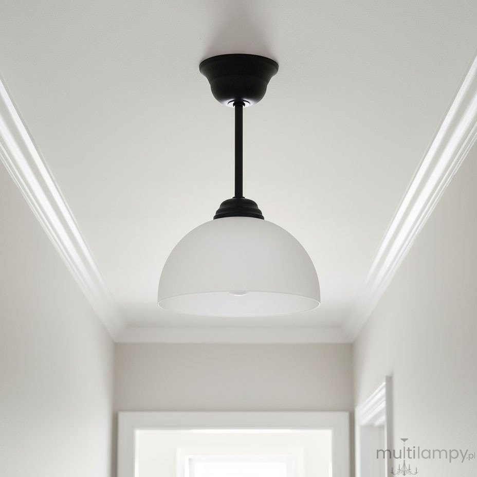Lampa wisząca Frella o konstrukcji czarnej z metalowym wykończeniem. Posiada biały klosz w kształcie półkuli, zamontowana na długim przewodzie. Widok z dołu na lampę, zawieszoną na tle jasnego sufitu i ścian.