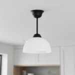 Lampa wisząca Frella z czarnym metalowym mocowaniem i białym, szklanym kloszem w kształcie półkuli. Zawieszona na cienkiej lince, idealna do nowoczesnych wnętrz. Ujęcie z dołu, na jednolitym tle.