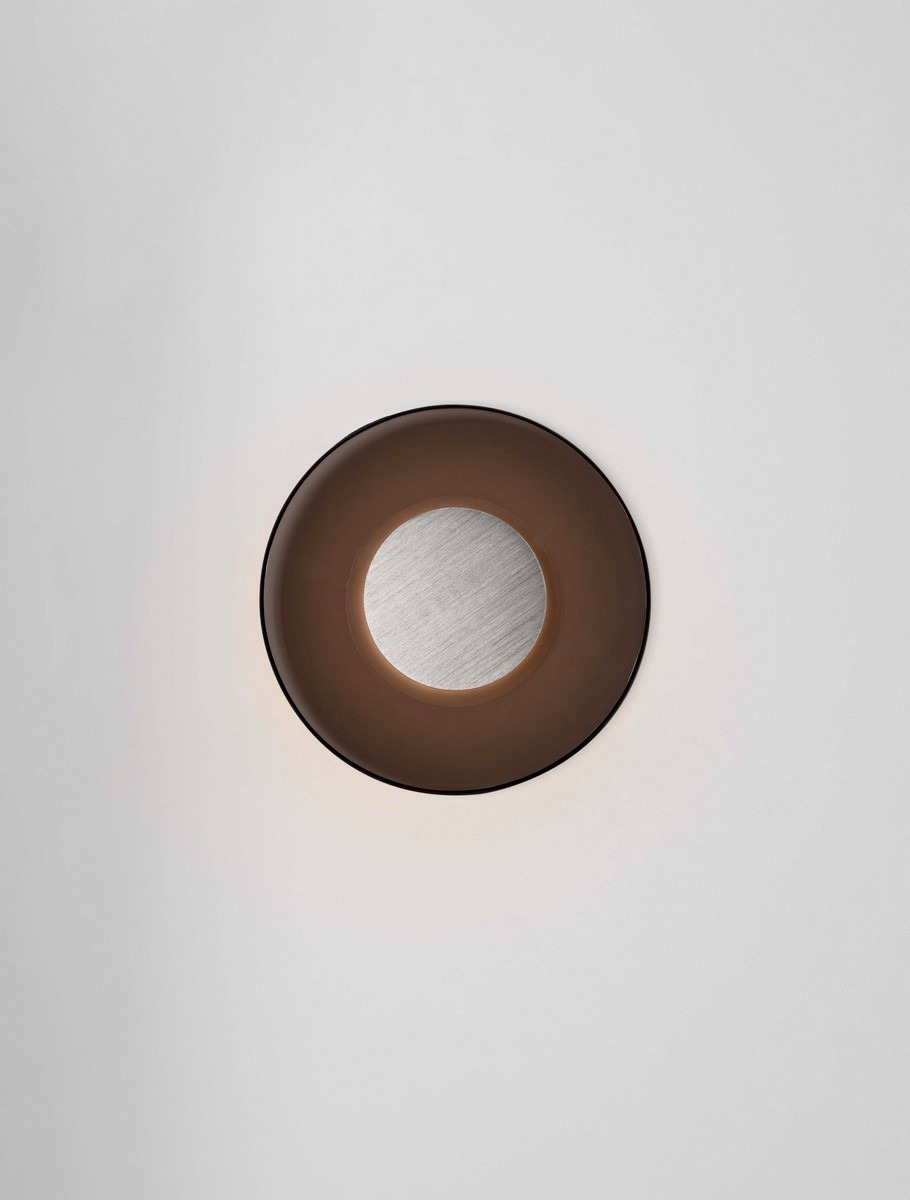 Kinkiet Huanuco 1xLED 17W w kolorze niklowym i brązowym, okrągły z matowym kloszem, zamontowany na białej ścianie. Środkowa część z metalicznym wykończeniem, emitujący ciepłe światło. Idealny do nowoczesnych wnętrz.