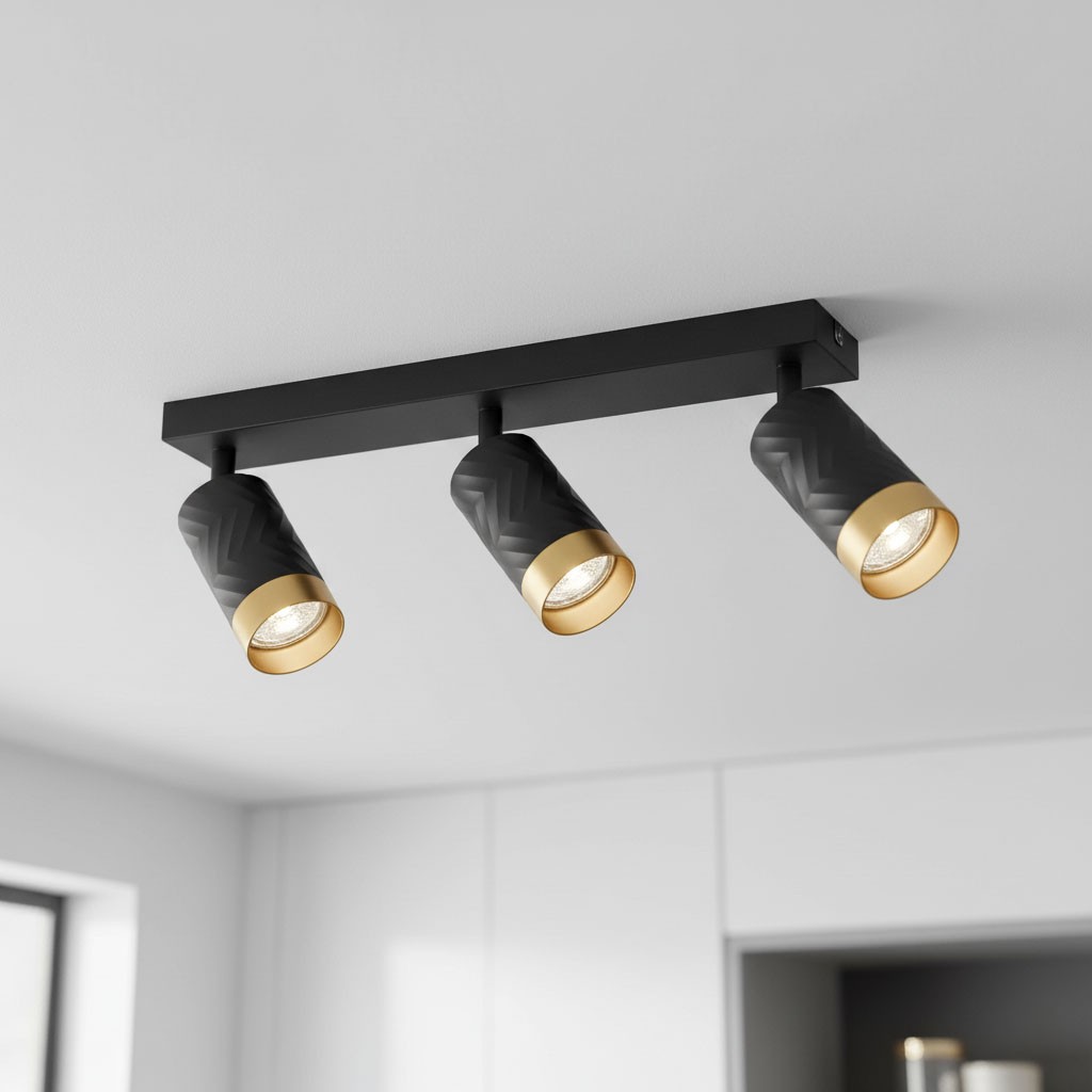 Lampa sufitowa Arras w kolorze czarnym z złotymi elementami, z trzema reflektorami GU10. Reflektory mają teksturowaną powierzchnię w wzór chevron. Ujęcie z góry, zamontowana na prostokątnej podstawie. Tło jasne, minimalistyczne.