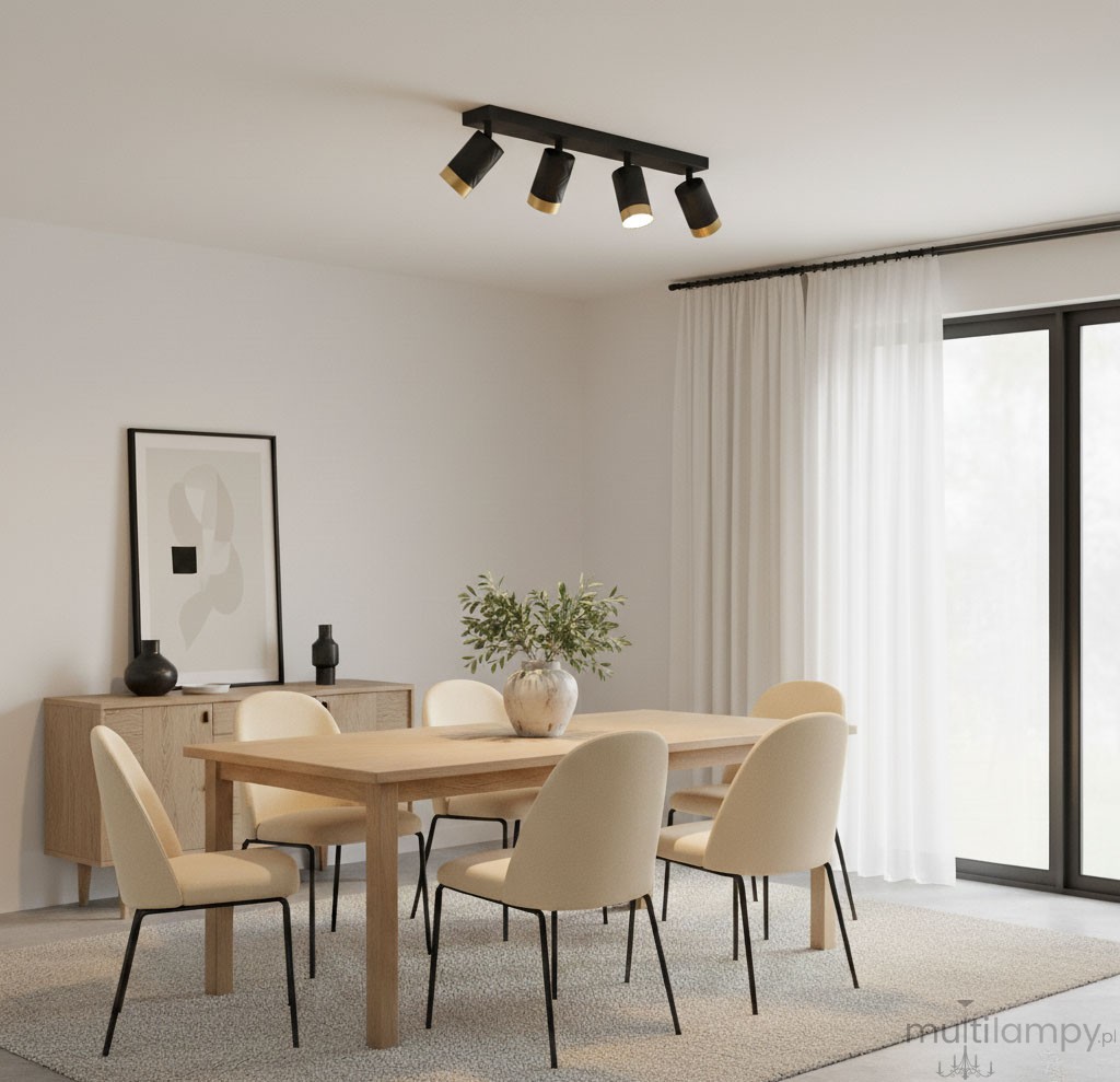 Czarna lampa sufitowa Arras z czterema reflektorami GU10, z elementami w złotym kolorze. Zamontowana na suficie, o nowoczesnym designie, w jasnym wnętrzu z drewnianym stołem i jasnymi krzesłami.