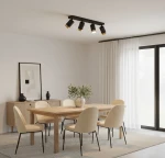Czarna lampa sufitowa Arras z czterema reflektorami GU10, z elementami w złotym kolorze. Zamontowana na suficie, o nowoczesnym designie, w jasnym wnętrzu z drewnianym stołem i jasnymi krzesłami.