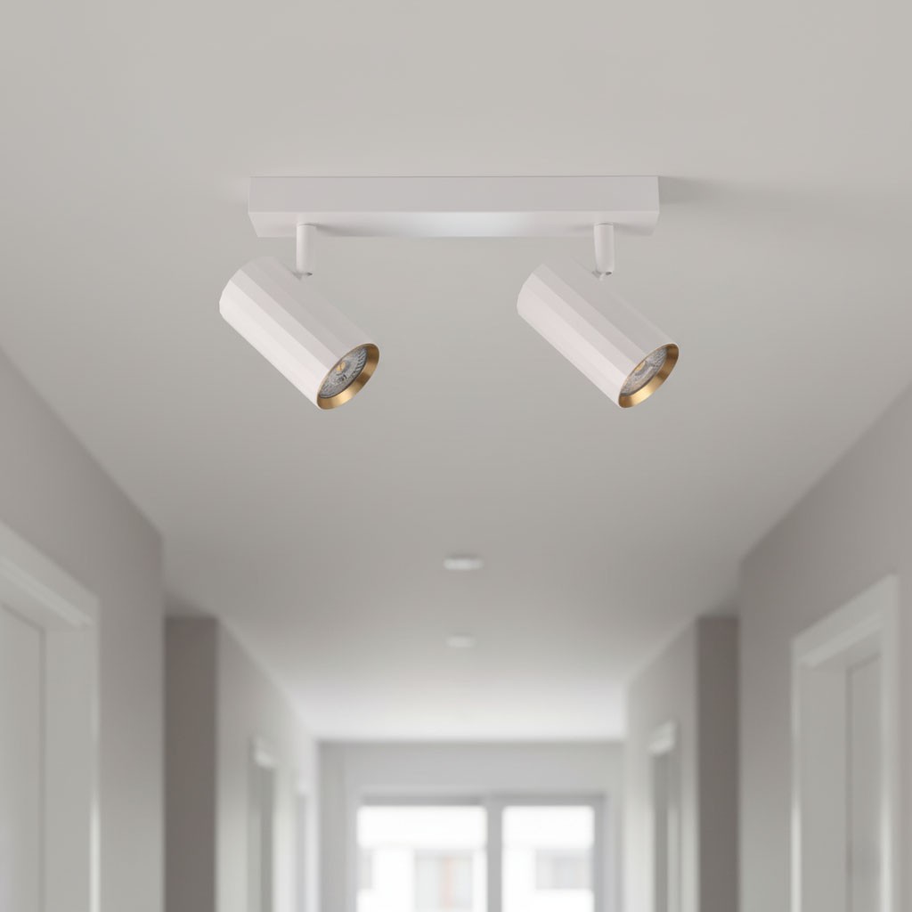 Lampa sufitowa Nicea w kolorze białym z złotymi akcentami, wyposażona w dwa reflektory GU10. Ujęcie z dołu, pokazujące lampę zamontowaną na suficie w korytarzu. Wysokie, cylindryczne klosze z błyszczącym wykończeniem.