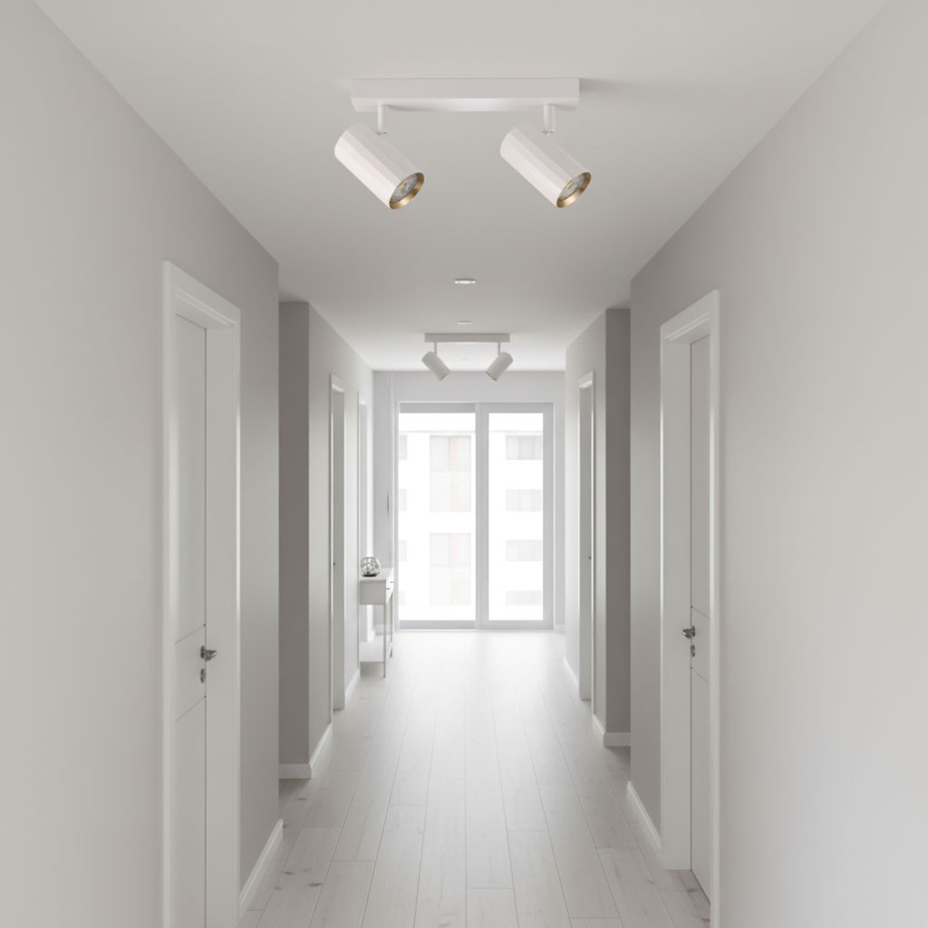 Lampa sufitowa Nicea z dwoma spotami GU10 w białej obudowie z złotym wnętrzem, zamontowana na suficie w jasnym korytarzu, oświetlająca przestrzeń. W tle widoczne drzwi i okna, na podłodze jasne deski.