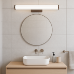 Kinkiet LED Vena 60 o mocy 12W w kolorze kawowym, zamontowany nad okrągłym lustrem. Posiada prostokątną, teksturowaną obudowę z białego materiału, idealny do łazienki, na tle jasnych płytek ceramicznych.