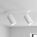 Lampa sufitowa Turyn IP44 w kolorze białym, z dwoma okrągłymi reflektorami na ruchomych ramionach, zamontowana na prostokątnej podstawie. Reflektory są przezroczyste na końcach, co umożliwia wykorzystanie żarówek GU10.
