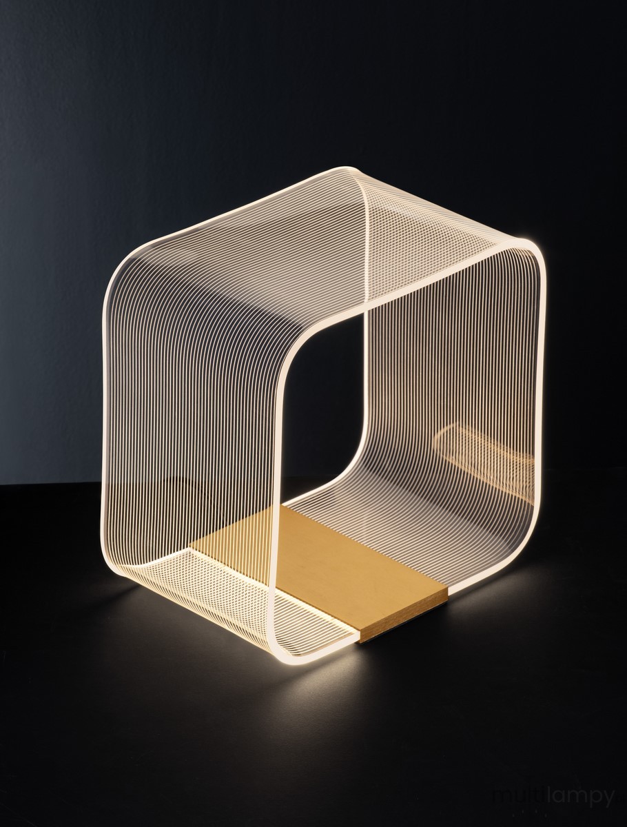 Lampa stołowa Huaral z LED 14W w złotym wykończeniu. Otwarta, nowoczesna konstrukcja z cienkich metalowych linii, emitująca ciepłe światło. Ustawiona na czarnej powierzchni, z widoczną złotą podstawą.