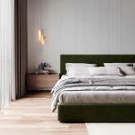 Huaral kinkiet 1xLED 9W w kolorze złotym, zamontowany na ścianie obok łóżka. Lampa ma nowoczesny, spiralny kształt, emitująca ciepłe światło. W tle widoczna jest zielona tapicerowana rama łóżka oraz drewniana szafka nocna.