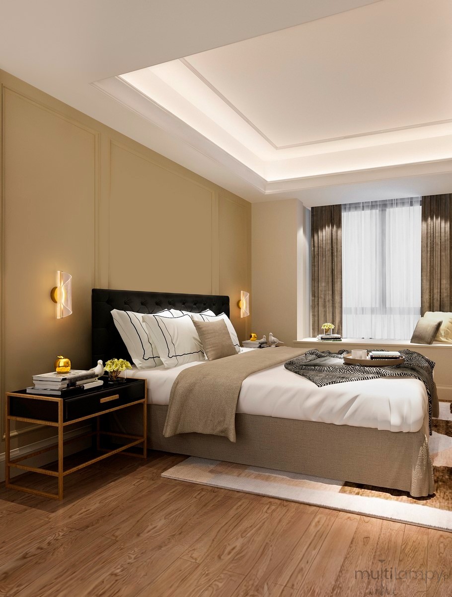 Kinkiet Huaral 1xLED 9W w kolorze złotym, zamontowany po obu stronach łóżka w eleganckiej sypialni. Świeci ciepłym światłem, podkreślając nowoczesny design i przytulną atmosferę. W tle widoczne meble i dekoracje w stonowanej kolorystyce.