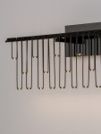 Kinkiet Huaraz 1xLED 11W w kolorze czarnym, składający się z długich, prostokątnych ramion. Światła LED umieszczone na końcach ramion emitują ciepłe światło. Produkt zamontowany na ścianie, z jednolitym, jasnym tłem.