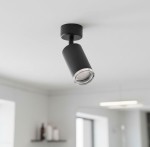 Czarna lampa sufitowa Turyn IP44 w formie spotu z jednym gniazdem GU10. Ujęcie z dołu, lampa zamontowana na suficie, o cylindrycznym kształcie z przezroczystym kloszem, emitującym światło. Tło jasne, minimalistyczne.