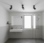 Lampa sufitowa Turyn IP44 w kolorze czarnym z jedną oprawą GU10, zamontowana na suficie w nowoczesnej łazience. Oświetlenie skierowane jest na lustro, w tle widoczne szare płytki oraz szklana kabina prysznicowa.