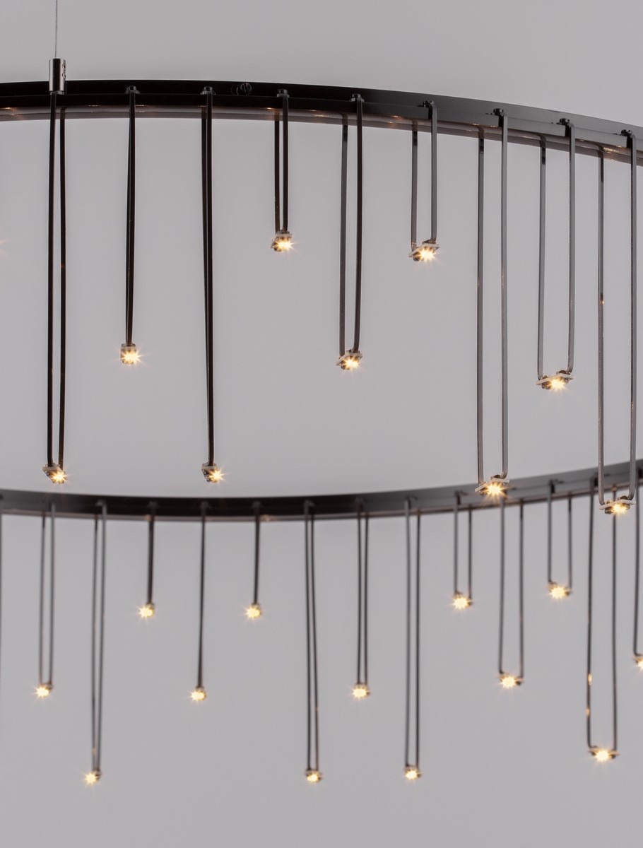 Czarna lampa wisząca Huaraz D80 z 1xLED 30W, z okrągłym metalowym stelażem i wiszącymi przewodami. Na końcach przewodów znajdują się małe diody LED, które emitują ciepłe światło. Lampa zawieszona jest na białym tle.
