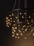 Lampa wisząca Huaraz 2xLED 41W w kolorze czarnym, z dwoma okrągłymi pierścieniami, na których zawieszone są lśniące źródła światła. Zbliżenie na elegancki design z widocznym efektem gwiazdy na tle ciemnej ściany.
