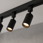 Zestaw szynowy 1m Tiger Track z trzema reflektorami w kolorze czarnym. Reflektory mają cylindryczny kształt, z widoczną złotą wewnętrzną częścią. Ujęcie z bliska, ukazujące detale i mocowanie na szynie. Tło neutralne, szare.