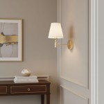 Kinkiet Astrit 1xE14 w kolorze złotym, z białym abażurem w kształcie stożka, zamontowany na ścianie. Obok widoczna drewniana komoda z dekoracyjnymi przedmiotami. Tło w neutralnym odcieniu, co podkreśla elegancję lampy.