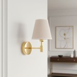 Kinkiet Astrit 1xE14 w kolorze złotym, z okrągłą podstawą i prostą, metalową ramą. Stylowy abażur w odcieniu beżowym. Ujęcie frontalne, montowany na ścianie, w tle minimalistyczne wnętrze.