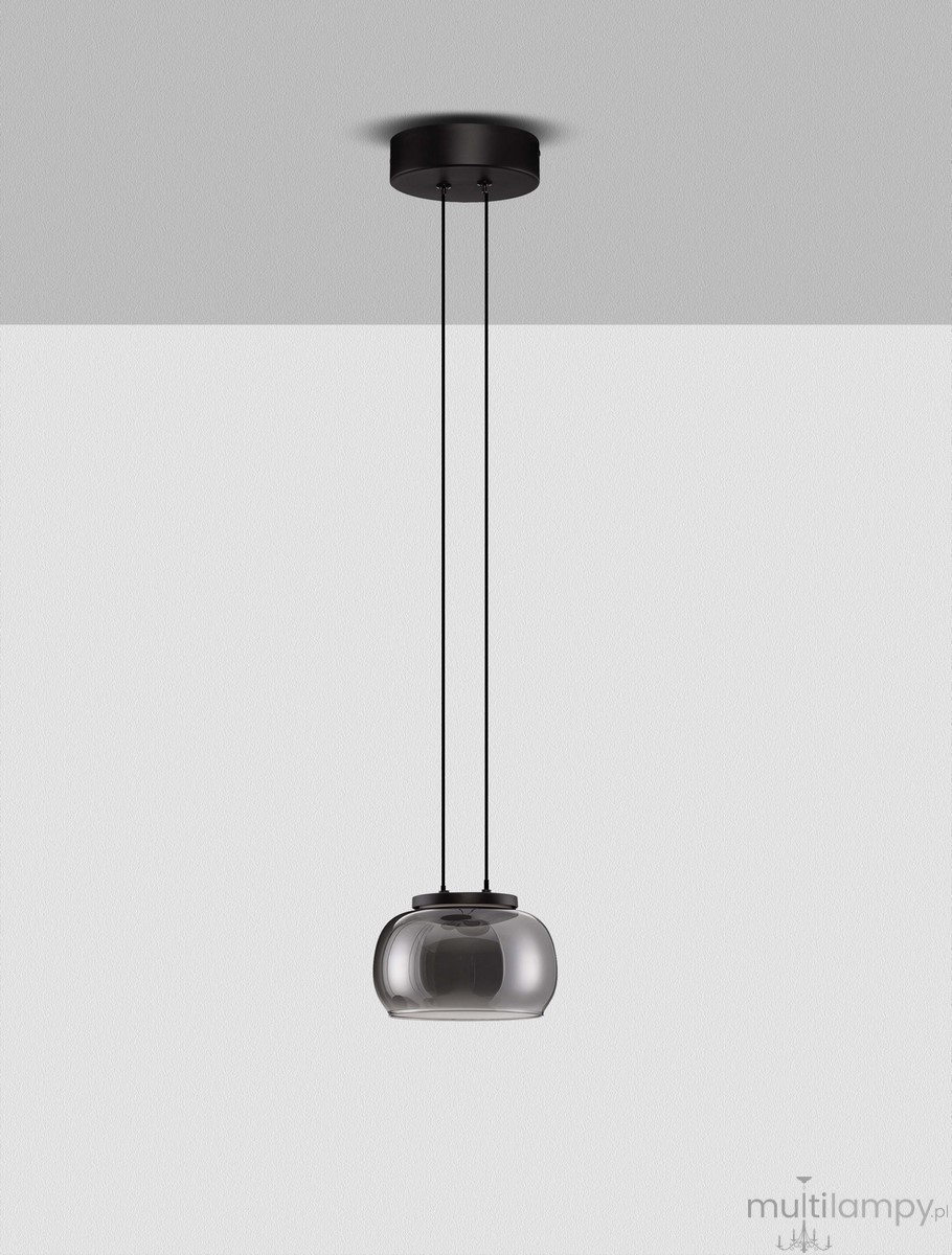 Lampa wisząca Huarmey z czarnym metalowym mocowaniem i przezroczystym kloszem w kształcie elipsy, zawieszona na dwóch cienkich linkach. Używa 1 żarówki LED 9W. Tło w jasnym kolorze.