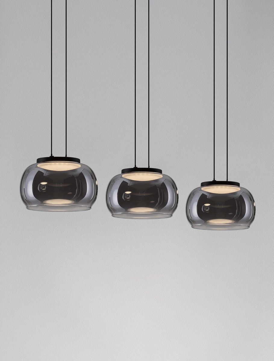 Lampa wisząca Huarmey z trzema kloszami LED 25W w kolorze czarnym. Klosze mają zaokrąglony kształt z przezroczystego szkła, zawieszone na cienkich czarnych linkach, w stonowanym otoczeniu szarości.