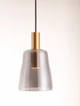Lampa wisząca Iquitos z przezroczystym kloszem z tworzywa sztucznego i złotym mocowaniem. Źródło światła LED 7W. Produkt zawieszony na czarnym kablu, z widoczną żarówką w centralnej części klosza. Minimalistyczny design, idealna do nowoczesnych wnętrz.