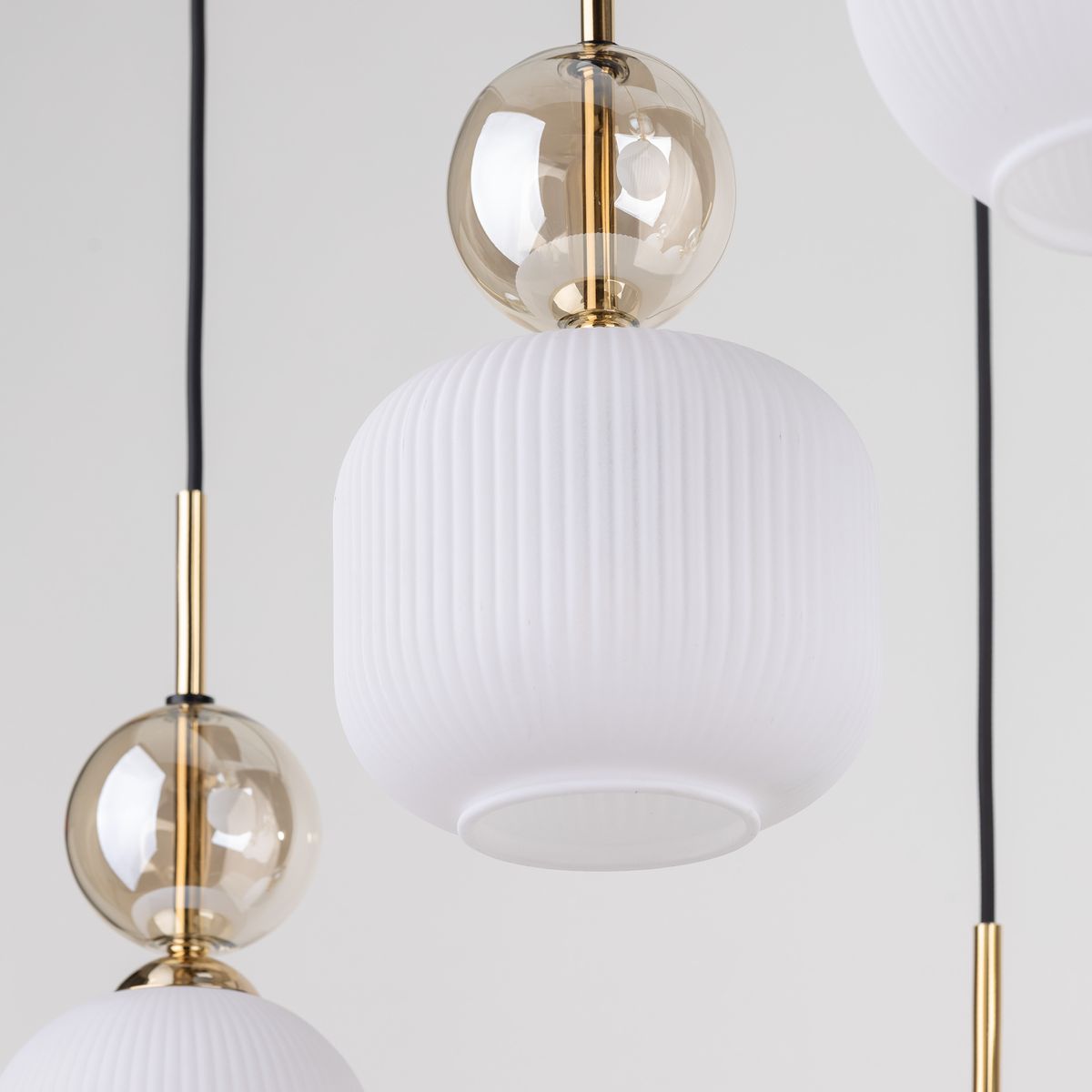 Lampa wisząca Sophia z sześcioma gniazdami E14, w kolorze białym. Posiada okrągły klosz z fakturą i przezroczystą kulę u góry, zawieszona na czarnym przewodzie. Elementy metalowe w kolorze złotym.