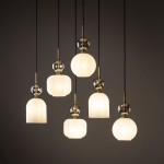 Lampa wisząca Sophia z sześcioma źródłami światła E14, w białej oprawie. Posiada różne kształty kloszy: cylindryczny, kulisty oraz prostokątny, z dekoracyjnymi elementami w kolorze złotym i przezroczystymi akcentami. Zawieszona na czarnych przewodach.