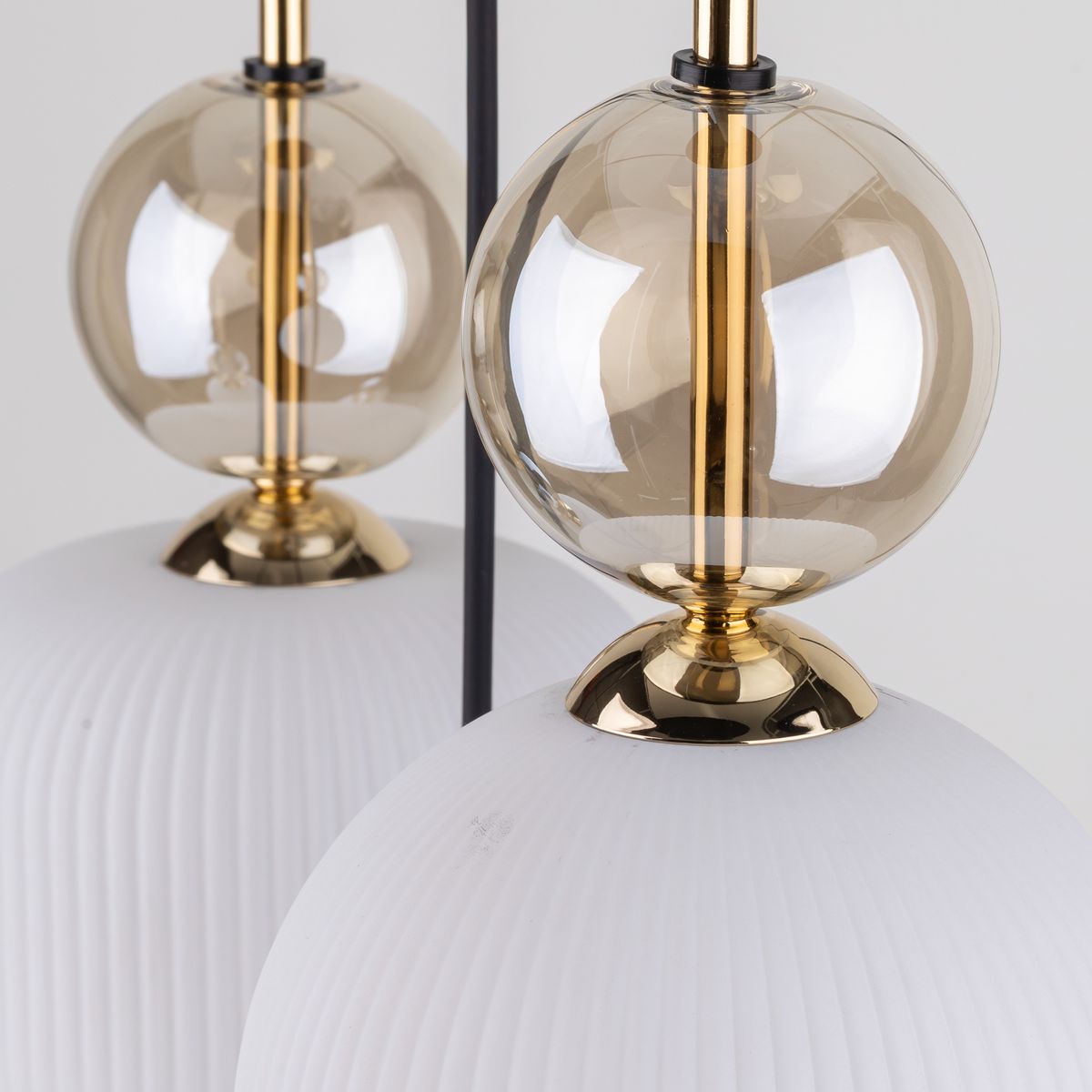 Lampa wisząca Sophia z pięcioma gniazdami E14, z białymi, teksturowanymi kloszami i przezroczystymi, złotymi kulami. Widoczna jest elegancka, złota podstawa, a całość zawieszona jest na czarnym przewodzie.