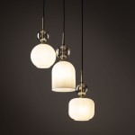 Biała lampa wisząca Sophia z trzema kloszami E14, w tym okrągłym i dwiema cylindrycznymi, z przezroczystymi detalami. Zawieszona na czarnych kablach, o matowej fakturze, idealna do nowoczesnych wnętrz.